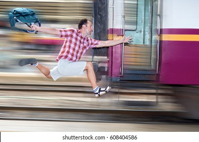 Tourist With Bag Running Behind The Train. A Man Runs For A Moving Wagon. Backpacker Hurries For Train Departing From The Station. Journey To The Last Minute.