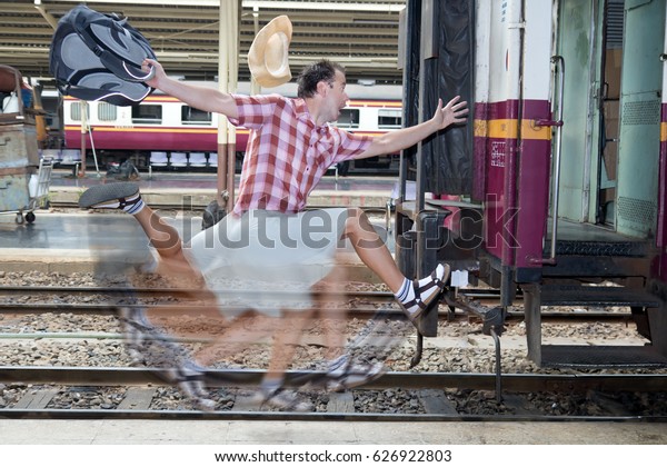 Tourist with bag running behind the\
train. A man runs for a wagon. Backpacker hurries for train\
departing from the station. Journey to the last\
minute.