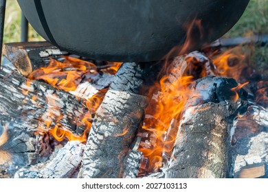 Tourist black cauldron with food on bonfire, cooking in the hike, outdoor activities. Preparation of pilaf or soup on fire, close up