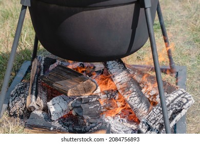 Tourist black cauldron with food on bonfire, cooking in the hike, outdoor activities. Preparation of pilaf or soup on fire, close up