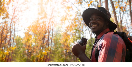 Tourist black skin man holding binoculars walking travel in the forest.  - Powered by Shutterstock