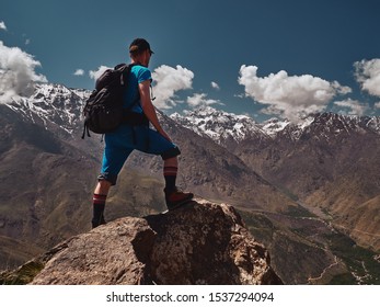 Tourist boy standing at the rock and watching Jebel Toubkal moutain in High Atlas, Morocco, Africa