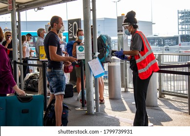 Tourist Buying Bus Ticket From Airport Worker, Both Wearing Mask And Keeping Distance Between Each Other. New Norm.Luton Airport, United Kingdom 13/08/2020