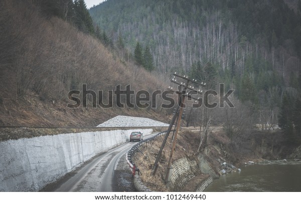 Tourist car on the\
winding roads of the mountains. The wild nature of the Carpathian\
Mountains in early\
spring