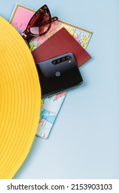 Tourist Card, Mobile Phone, Passport And Glasses Lie On A Blue Background, Covered With A Yellow Hat