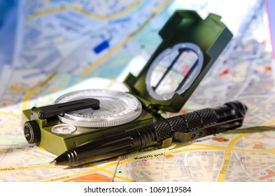 Tourist Compass And Tactical Pen Lying On The Map. Closeup.