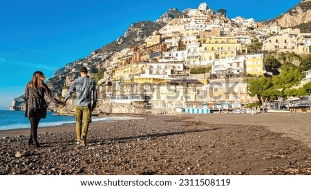 Tourist couple enjoying view on empty Marina Grande Beach and colorful buildings of hillside village Positano, Amalfi Coast, Italy, Campania, Europe. Luxury vacation at Tyrrhenian, Mediterranean Sea