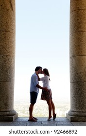 tourist couple kiss each other while visiting an old monument while traveling. a real young couple in love