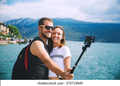 Tourist, couple of lovers making selfie photo on motion camera at Lake Garda, Italy, Europe. Holidays and Travel Concept. Happy couple recording their trip with action camera.