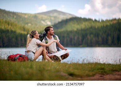 Tourist couple with map looking at lake. Summer trip in nature. Lifestyle, togetherness, nature concept - Shutterstock ID 2134757097