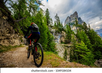Tourist cycling in Cortina d'Ampezzo, stunning rocky mountains on the background. Woman riding MTB enduro flow trail. South Tyrol province of Italy, Dolomites. - Shutterstock ID 1049184104
