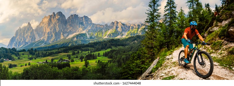 Tourist cycling in Cortina d'Ampezzo, stunning rocky mountains on the background. Man riding MTB enduro flow trail. South Tyrol province of Italy, Dolomites. - Shutterstock ID 1627444048
