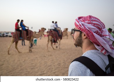 Tourist In The Dubai Desert Looking At A Camel Ride.