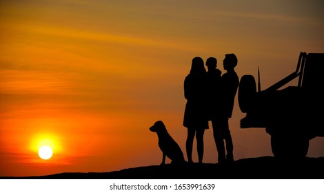 The tourist family and his dog are standing by the car, watching the sunset. Silhouette - Powered by Shutterstock