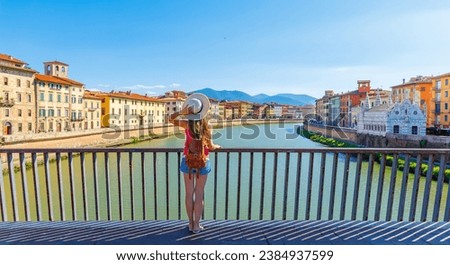 Tourist female in Pisa, Arno river, lamp and buildings reflection. Lungarno view.santa maria della spina