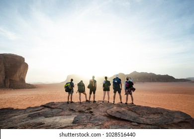 Tourist friends on a top of mountains in a desert. Sunset view. Nature. Tourist people enjoy a moment in a nature. Wadi rum national park - Jordan  - Shutterstock ID 1028516440