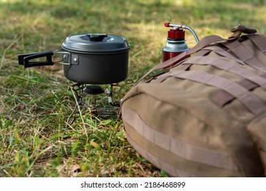 tourist gas burner with a tourist pan working installed on the ground against the background of green grass