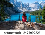 Tourist girl sitting in front of the Moraine Lake in Canada