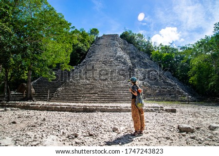 Tourist girl stands with her back against the background of Nohoch mul, mayan pyramid in Coba. Coba Archeological Area, Yucatan, Mexico 