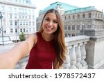 Tourist girl takes self portrait in Vienna with famous historic palaces State Opera and Hotel Sacher, Austria, Europe