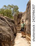 A tourist halfway up the stone stairs between huge granite boulders on the path to a lookout over the sea at Horseshoe Bay in Bowen in the Whitsunday region of tropical Queensland, Australia.