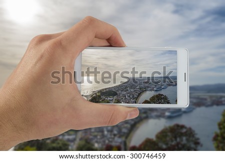 Tourist hand holding smart phone, taking photo of Auckland New Zealand, Rangitoto island