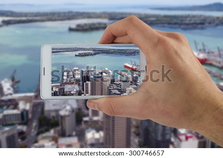 Tourist hand holding smart phone, taking photo of Auckland New Zealand, Devonport