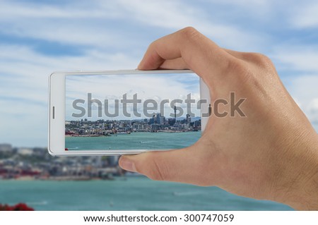 Tourist hand holding smart phone, taking photo of Auckland New Zealand, Devonport