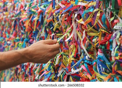 Tourist hand touching colorful Senhor do Bonfim ribbons at Pelourinho in Salvador, Bahia, Brazil.