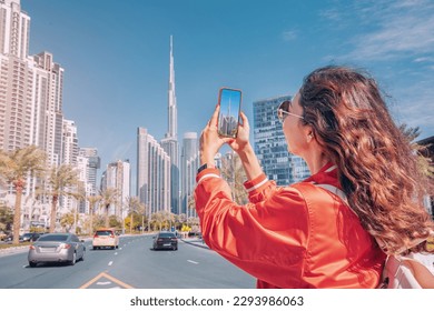 Tourist happy girl taking photos for her travel blog, in Dubai downtown district against background of the Burj Khalifa highest skyscraper