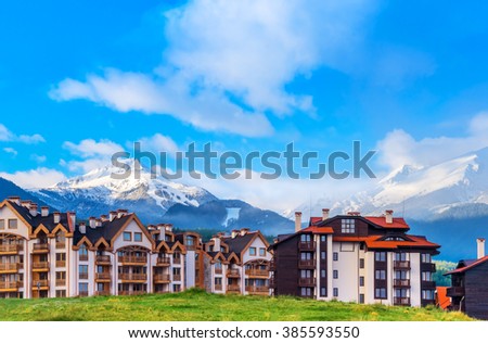 Tourist hotels on a background of panorama of green mountains and blue sky in the morning at dawn in summer. Beautiful facades of ski resort buildings in Bansko, Bulgaria. Tourism. Travel