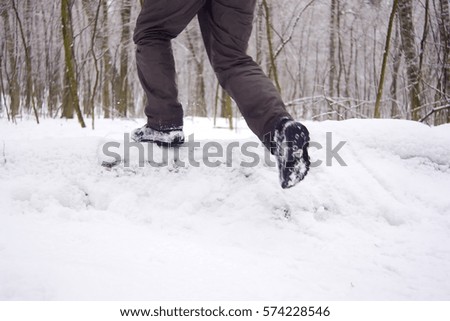 tourist jumps over a log in the winter forest a