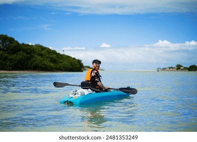 tourist in kayak with paddle next to pelicans flying over the sea in a tropical bay - Powered by Shutterstock