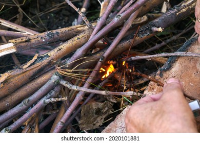 Tourist kindles a small fire with matches, close-up photography of branches, fire, hands with a matchbox