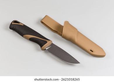 Tourist knife with classic fixed blade with a protective gray coating and ergonomic plastic handle and its plastic sheath lie on a gray background

