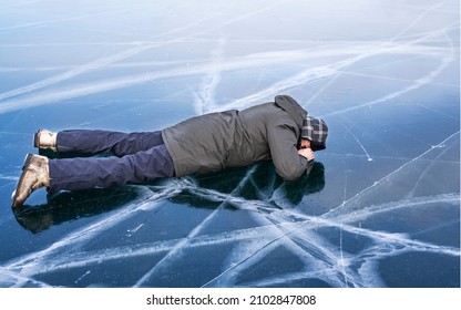 Tourist lies face down on the frozen ice of Lake Baikal. Baikal ice is so clean and transparent that you can see the bottom through it.
