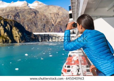 Tourist looking at Alaska Glacier Bay nature landscape using binoculars on cruise ship. Whale watching from boat. Luxury travel in USA.