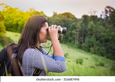 Tourist looking through binoculars considers wild birds in the Khao yai national park Thailand
