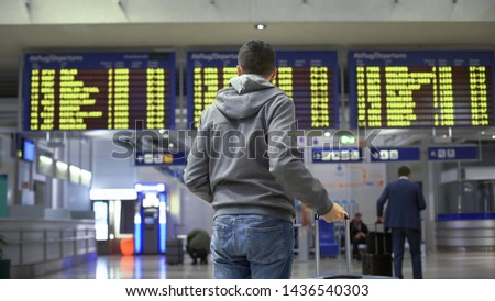 Tourist looking at time table, checking schedule on screen in bus terminal