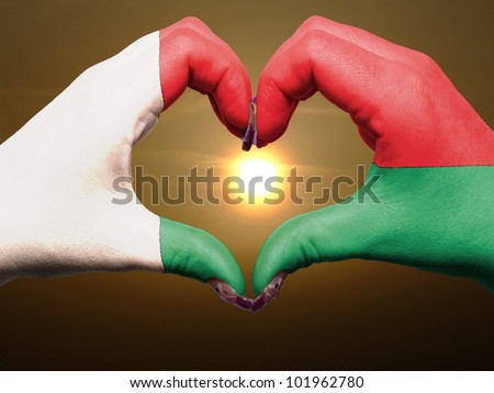 Tourist made gesture  by madagascar flag colored hands showing symbol of heart and love during sunrise