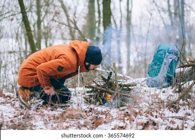 A Tourist Is Making Camp Fire In The Winter Woods
