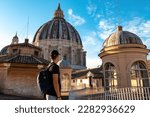 Tourist man with detailed close up view on Michelangelos Dome of St Peter Basilica in Vatican City, Rome, Lazio, Europe, EU. Architectural masterpiece of Papal Basilica of Saint Peter on sunny day