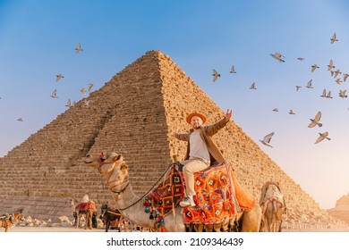 Tourist man with hat riding on camel background pyramid of Egyptian Giza, sunset Cairo, Egypt. - Shutterstock ID 2109346439