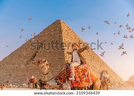 Tourist man with hat riding on camel background pyramid of Egyptian Giza, sunset Cairo, Egypt.