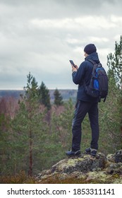 Tourist Mann draußen, der Informationen in Smartphone sucht. Waldhintergrund unscharf.