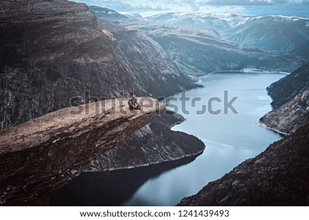 Similar – Man sitting on a cliff of a fjord with low sun on the European Arctic Ocean