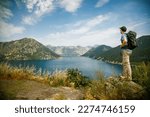 Tourist man standing on the edge of a cliff, enjoying amazing sea view of the Bay of Kotor, Montenegro