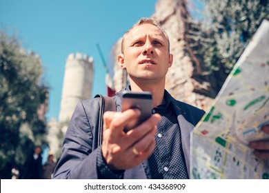 Tourist man try navigate himself with map and smartphone in unknown city