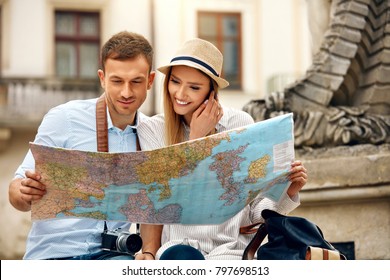 Tourist Man And Woman With Map On City Street. Beautiful Smiling Couple In Love Holding Map In Hands While Traveling Together. Travel Concept. High Resolution.