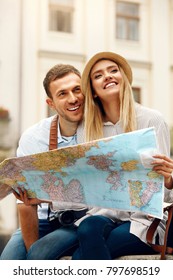 Tourist Man And Woman With Map On City Street. Beautiful Smiling Couple In Love Holding Map In Hands While Traveling Together. Travel Concept. High Resolution.